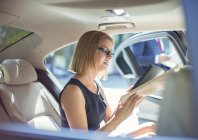 Donna d'affari che utilizza tablet digitale sul sedile posteriore dell'auto — Foto stock