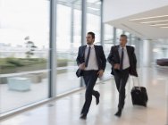 Empresarios corriendo, corriendo con la maleta en el aeropuerto - foto de stock