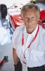 Portrait confident formula one racing manager in repair garage — Stock Photo