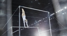 Female gymnast performing on uneven bars in arena — Stock Photo