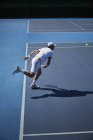 Теннисист играет в теннис на солнечном синем теннисном корте — стоковое фото