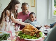 Многонациональная семья наслаждается рождественским ужином с индейкой за столом — стоковое фото