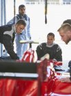 Формула-1 водій спостерігає за екіпажем піт-команди по ремонту гоночного автомобіля в ремонтному гаражі — стокове фото