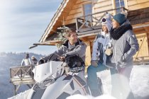 Friends with snowmobile outside sunny cabin — Stock Photo