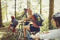 Portrait smiling mother mountain biking with family in woods — Stock Photo