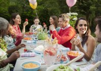 Family and friends enjoying birthday garden party at patio table — Stock Photo