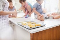 Madre e hijos horneando galletas en la cocina - foto de stock