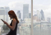 Donna d'affari che utilizza tablet digitale alla finestra urbana con vista sulla città, Londra, Regno Unito — Foto stock