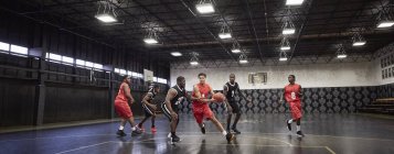 Junge männliche Basketballer spielen auf dem Platz in der Sporthalle — Stockfoto