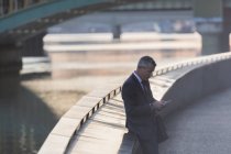 Businessman texting with cell phone at urban waterfront — Stock Photo