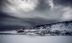 Kirche in abgelegener, schneebedeckter Landschaft unter stürmischem Himmel, vik, Island — Stockfoto