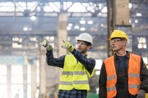 Trabajadores del acero hablando y señalando en fábrica - foto de stock