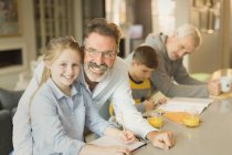 Portrait male gay parents helping children with homework at kitchen counter — Stock Photo