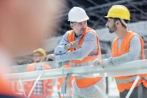 Male foreman and construction worker talking at construction site — Stock Photo