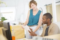 Woman and man looking at documents, talking and smiling in office — Stock Photo