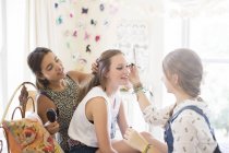 Три девочки-подростки делают макияж и расчесывают волосы в спальне — стоковое фото