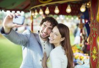 Couple souriant prenant selfie dans le parc d'attractions — Photo de stock
