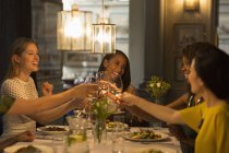 Souriantes femmes amies griller des verres à vin blanc dîner à la table du restaurant — Photo de stock