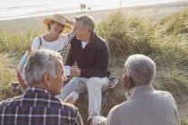 Senior couples drinking coffee and relaxing on beach — Stock Photo