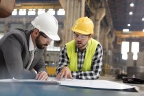 Manager and engineer reviewing blueprints in steel factory — Stock Photo
