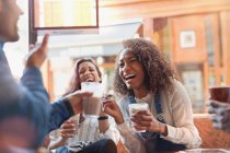 Смеющиеся юные друзья пьют молочные коктейли в кафе — стоковое фото