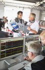 Formula one team reviewing diagnostics in repair garage — Stock Photo