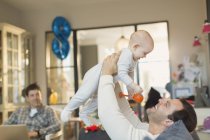 Male gay parents playing with baby son in living room — Stock Photo