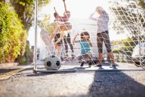 Amis jouant au football sur la rue ensoleillée d'été urbaine — Photo de stock