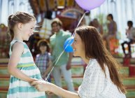 Mãe e menina com balão olhando um para o outro no parque de diversões — Fotografia de Stock