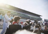 Команда Формулы-1 и гонщик, распыляющие шампанское, празднующие победу на спортивной трассе — стоковое фото