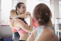 Smiling young woman stretching arm and shoulder in gym — Stock Photo