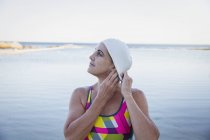 Жіночий плавець коректує шапку на океані на відкритому повітрі — стокове фото