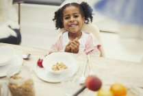 Portrait smiling girl eating breakfast at table — Stock Photo