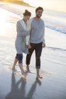 Giovane coppia a piedi sulla spiaggia al sole della sera — Foto stock