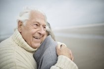 Liebevolles Senioren-Paar umarmt sich am Winterstrand — Stockfoto