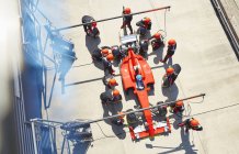 Tripulación aérea reemplazando neumáticos en Fórmula 1 coche de carreras en pit lane - foto de stock