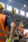 Steel workers operating crane in factory — Stock Photo