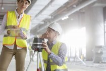 Engineers with digital tablet and theodolite surveying construction site — Stock Photo