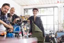 Retrato sorridente masculino e feminino motocicleta mecânica na oficina — Fotografia de Stock
