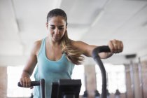 Focused young woman using elliptical trainer in gym — Stock Photo