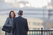Businessman and businesswoman talking at urban railing — Stock Photo