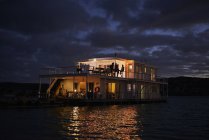 Летний плавучий дом, освещенный в ночном океане — стоковое фото
