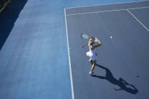 Молодая теннисистка, играющая в теннис на солнечном синем теннисном корте — стоковое фото
