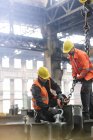 Steel workers fastening crane chain to steel in factory — Stock Photo