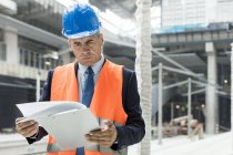 Businessman reviewing paperwork on clipboard at construction site — Stock Photo