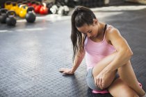 Молода, м'язова жінка розтягується, скручується в спортзалі — стокове фото