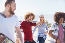 Smiling friends hanging out at sunny skate park — Stock Photo