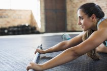 Young woman stretching with barbell in gym — Stock Photo