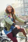 Portrait jeune femme ludique à vélo le long du canal urbain — Photo de stock