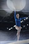 Female gymnast performing on balance beam in arena — Stock Photo